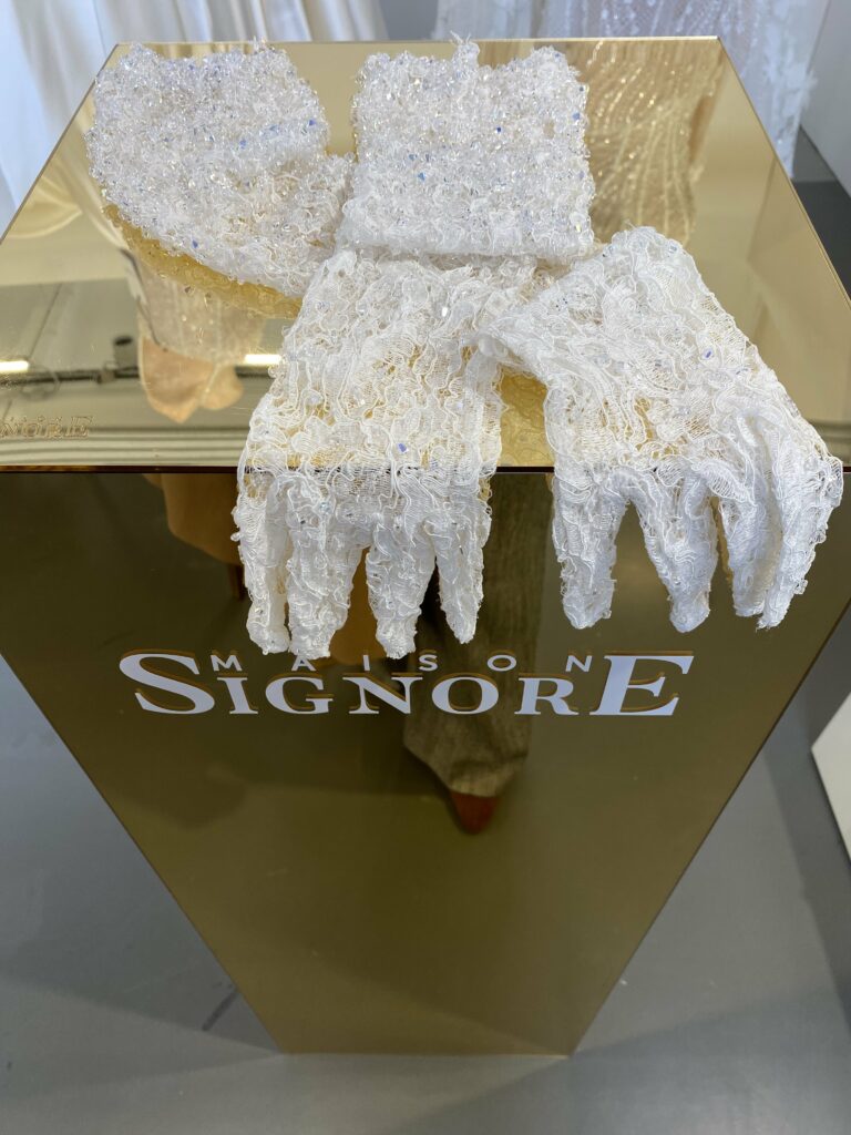 Foto de guantes de encaje y bordados sobre fondo color oro de Maison Signore